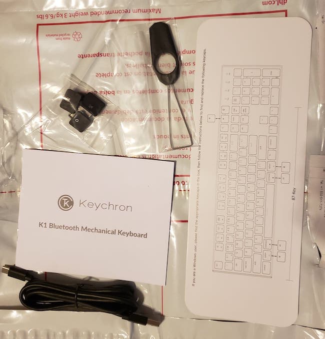 Contents of the box.  Key puller, manual, USB-A to C cable, key caps and a keyboard layout diagram.